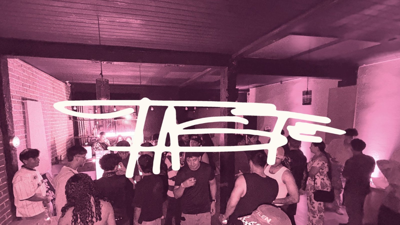 Logo de TASTE sobre una foto de la primera edición: artistas y público conviviendo en un salón con paredes de ladrillo e iluminación rosada